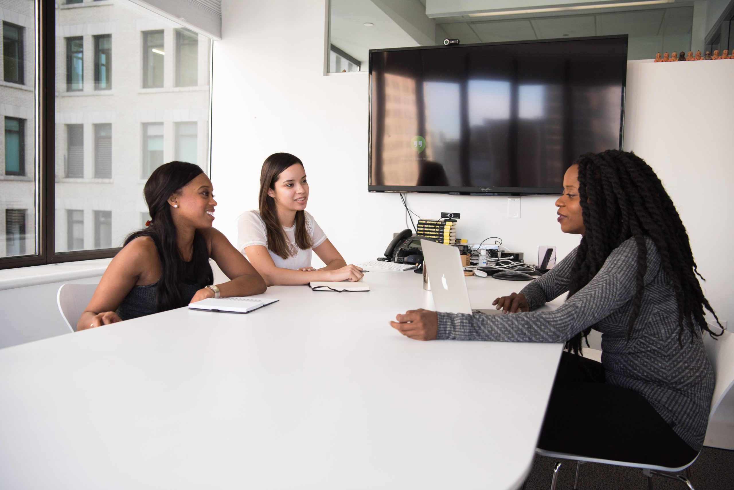 women of color sitting around a table in an office having a meeting