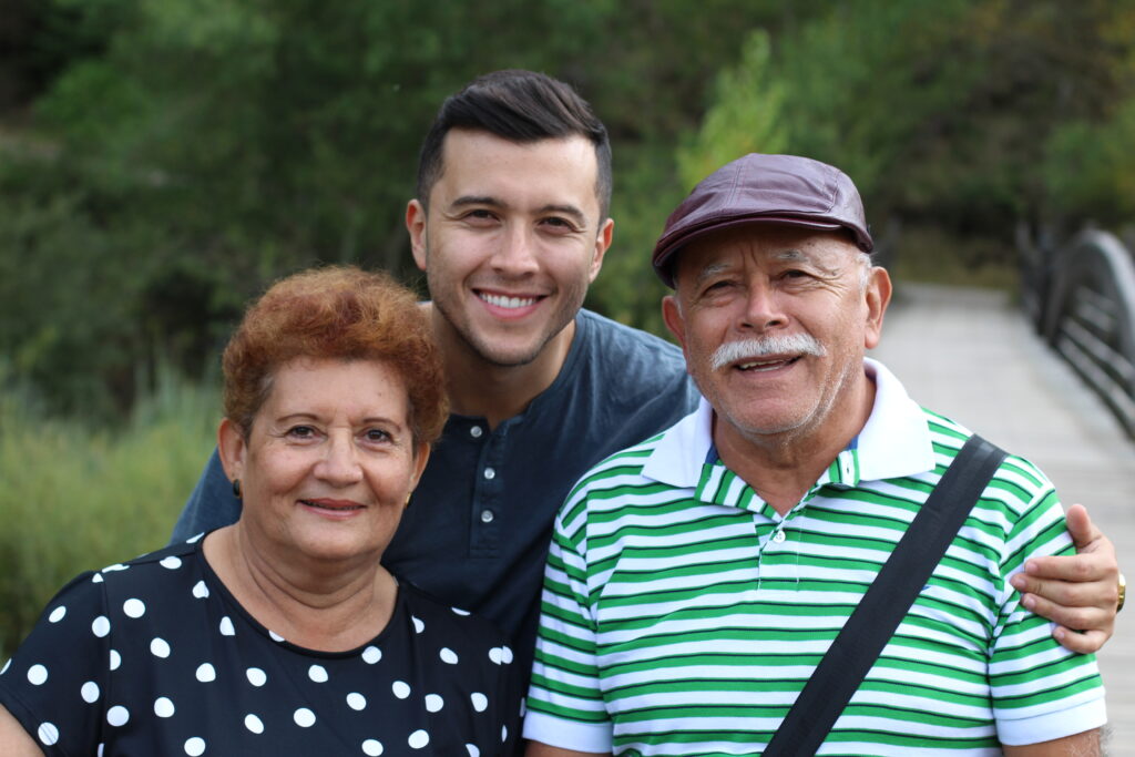 man who is sponsoring his parents to come to the us, hispanic man with his hispanic parents smiling outside