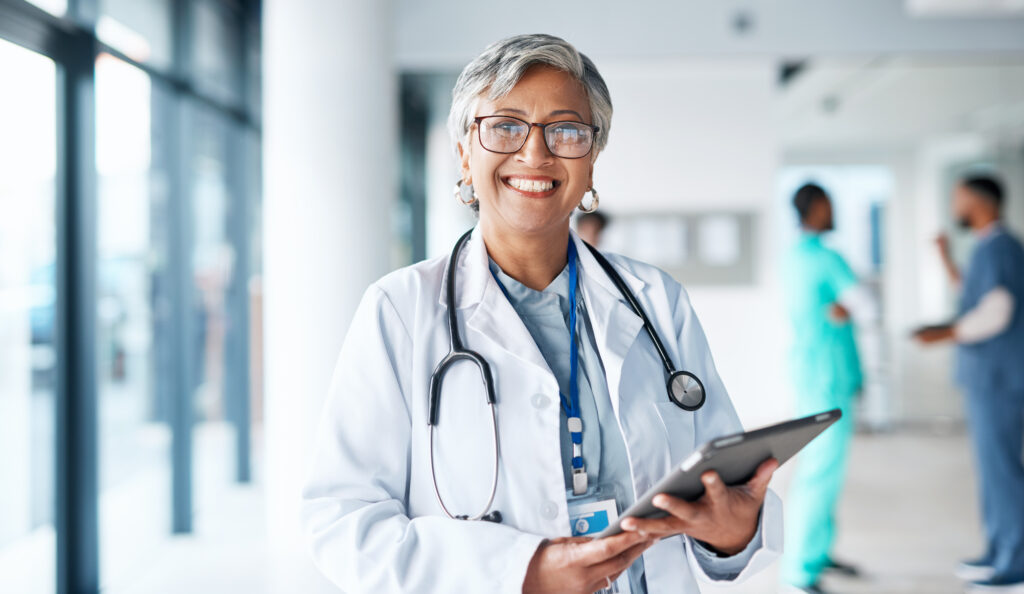 Portrait, healthcare and tablet with a doctor woman at work in a hospital for research or innovation. Medical, insurance and internet with a female medicine professional standing in a clinic, hb1 visa holder