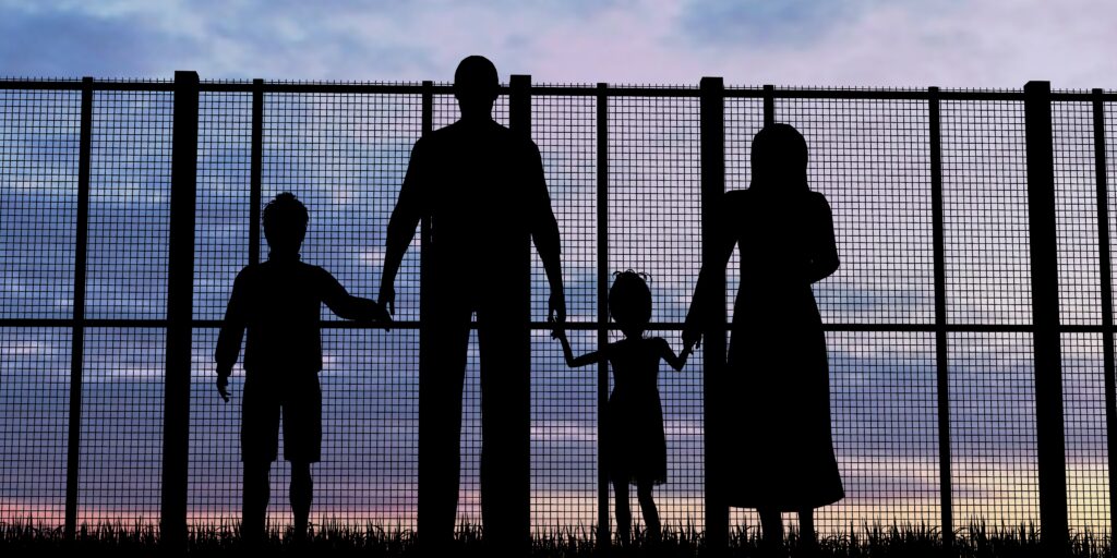 ill family members in need of humanitarian relief standing behind a fence in sunset