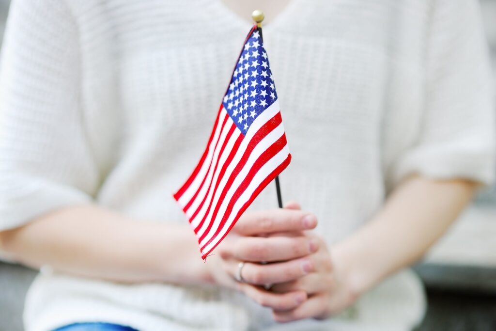 person in a white sweater holding an American flag.