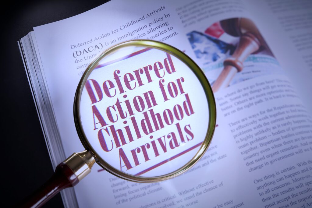 A page of a book with a magnifying glass above it, highlighting the words "Deferred Action for Childhood Arrivals".