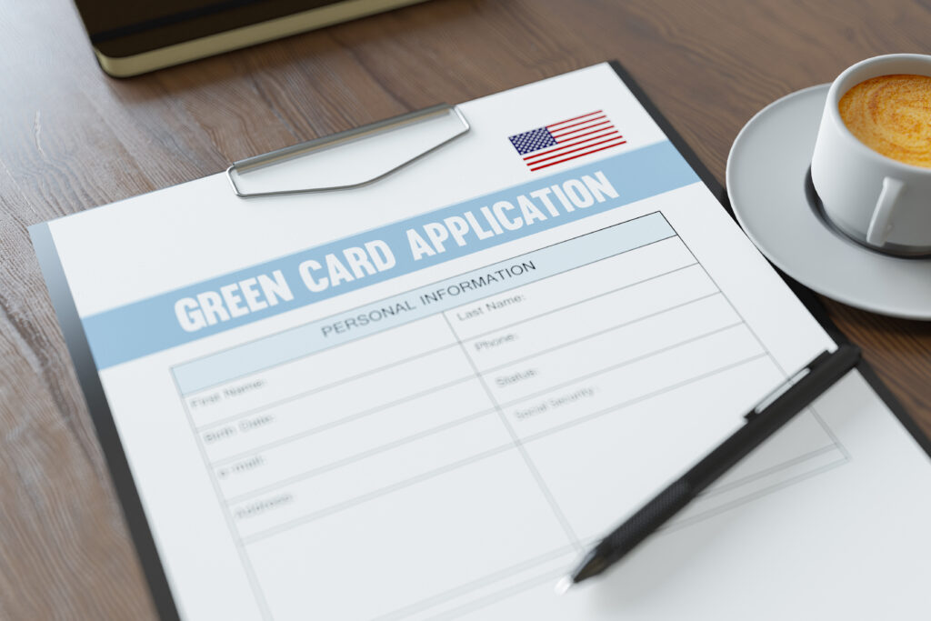 a green card application on a clipboard with a cup of coffee next to it.