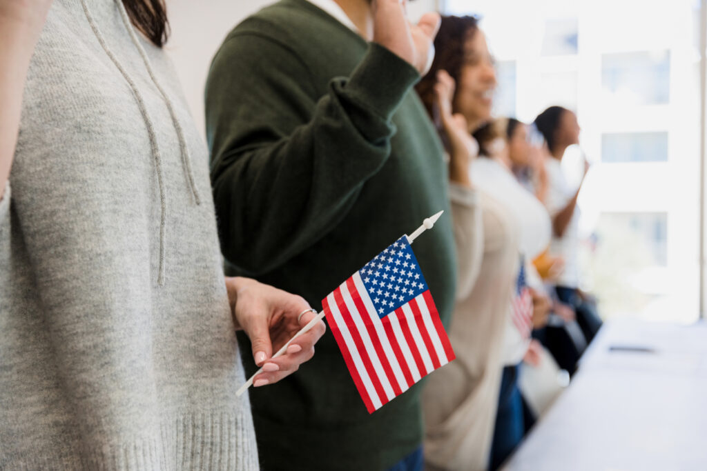 The group of immigrants stand and raise their hand to say the pledge for naturalization purposes