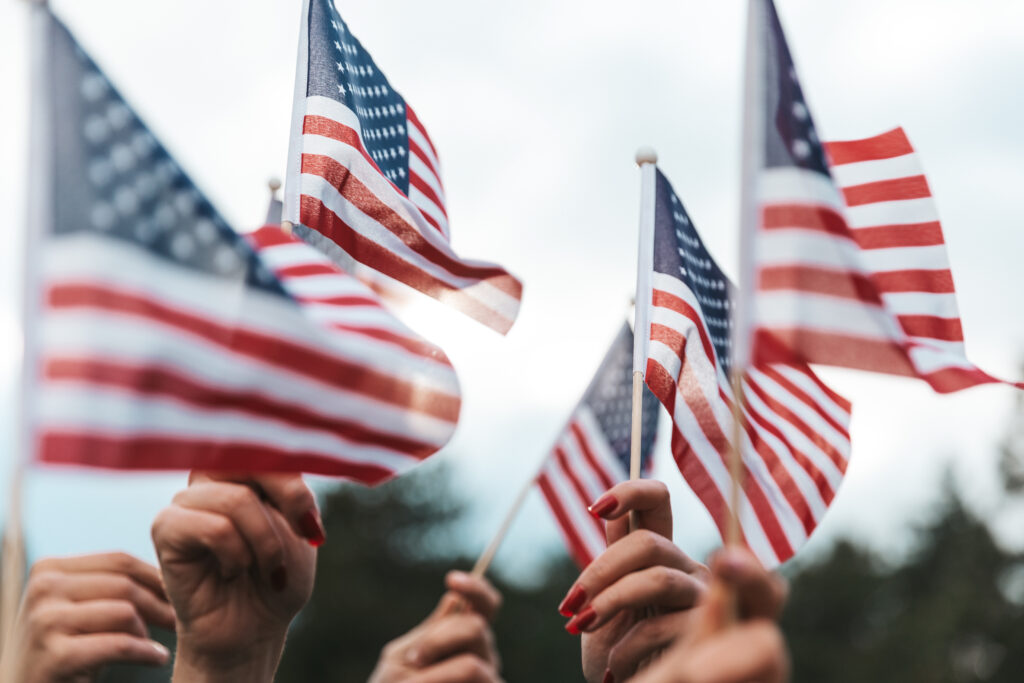 American flags raised by workers, close up of hands and flags, immigration concept of employment based green cards,