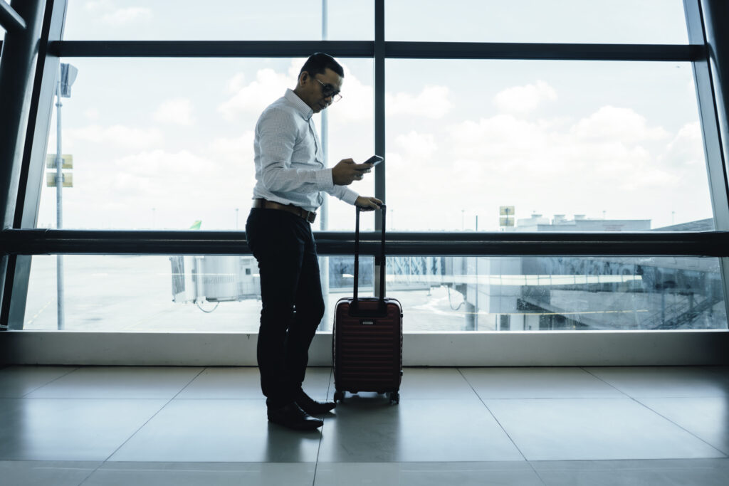 L1 visa intracompany transfer Businessman with smart phone standing at the airport and reading messages