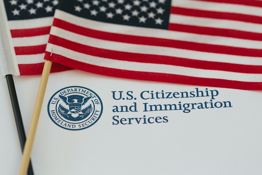USCIS visa process, upclose image of a paper from USCIS and american flags laying on it