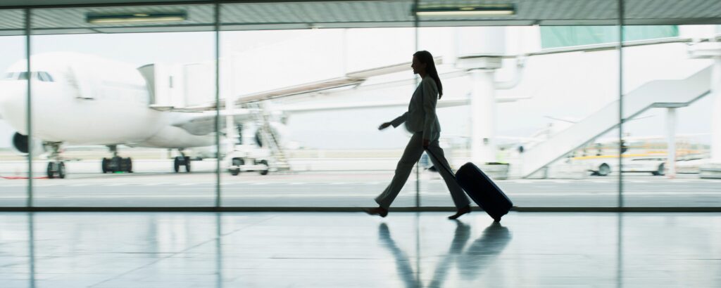 worker in the hotel industry (hospitality management) traveling for their job on a visa, worker walking through an airport with a suitcase.